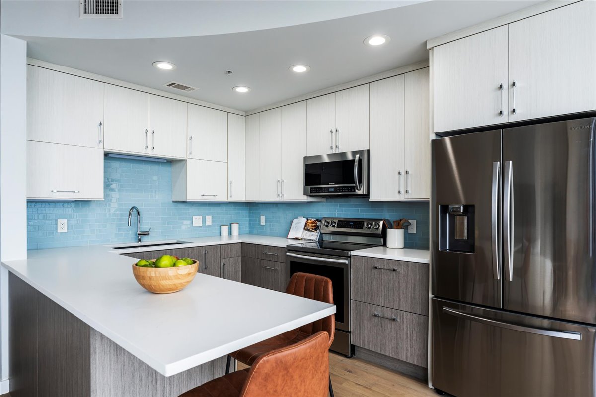 360 Nueces Street, Unit 4203 Austin, TX 78701 - Photo 20 of 40 Kitchen featuring stainless steel appliances, a peninsula, light countertops, a breakfast bar area, and white cabinets