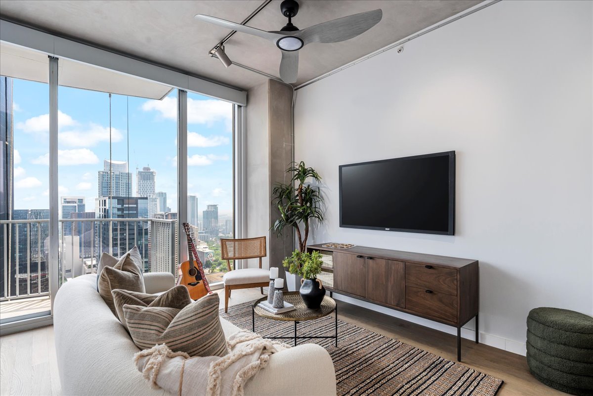 360 Nueces Street, Unit 4203 Austin, TX 78701 - Photo 10 of 40 Living area featuring wood finished floors, expansive windows, ceiling fan & art wall