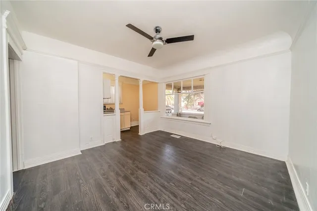 a view of an empty room with a window and wooden floor