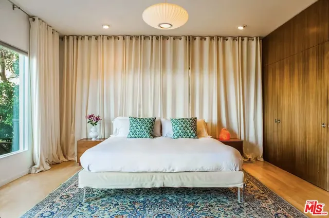 a bed sitting in a spacious bedroom next to a window