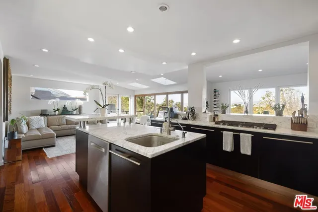 a kitchen with counter top space sink stove and wooden floor
