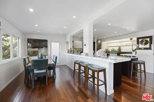 a dining room with stainless steel appliances granite countertop a table chairs and a wooden floor