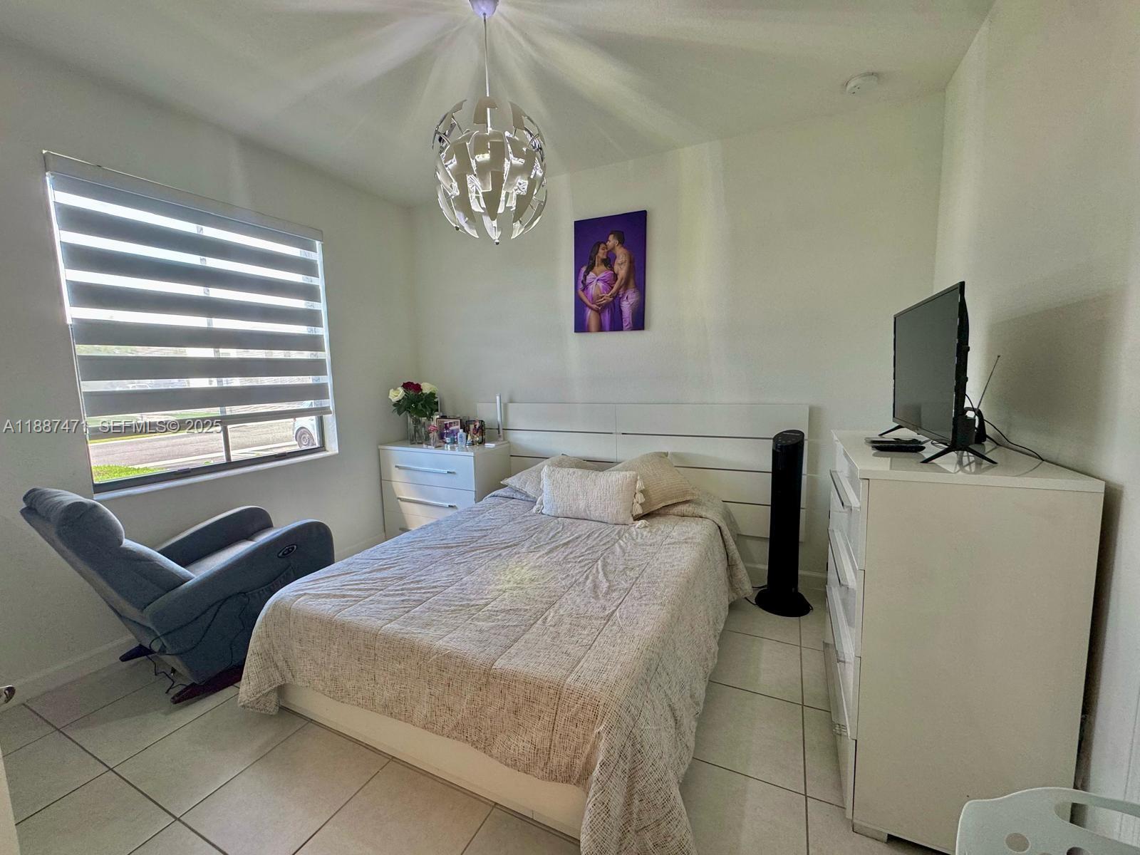 23541 Southwest 127th Place Homestead, FL 33032 - Photo 7 of 13 a bedroom with a bed and a chandelier