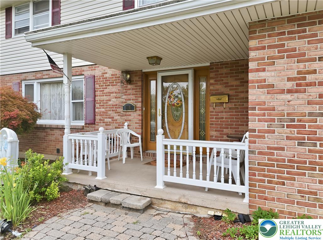 A welcoming covered front porch with white railings and brick accents creates an inviting entry to this residence.
