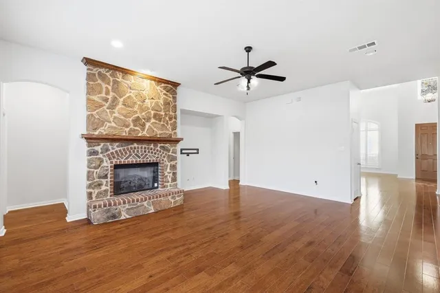 a view of an empty room with wooden floor a fireplace and a window