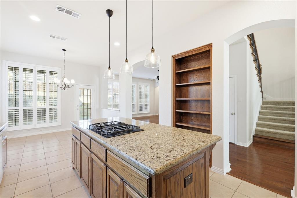 9728 Sam Bass Trail Fort Worth, TX 76244 - Photo 8 of 34 Kitchen with built in shelves, a kitchen island, light stone counters, open shelves and dining area.