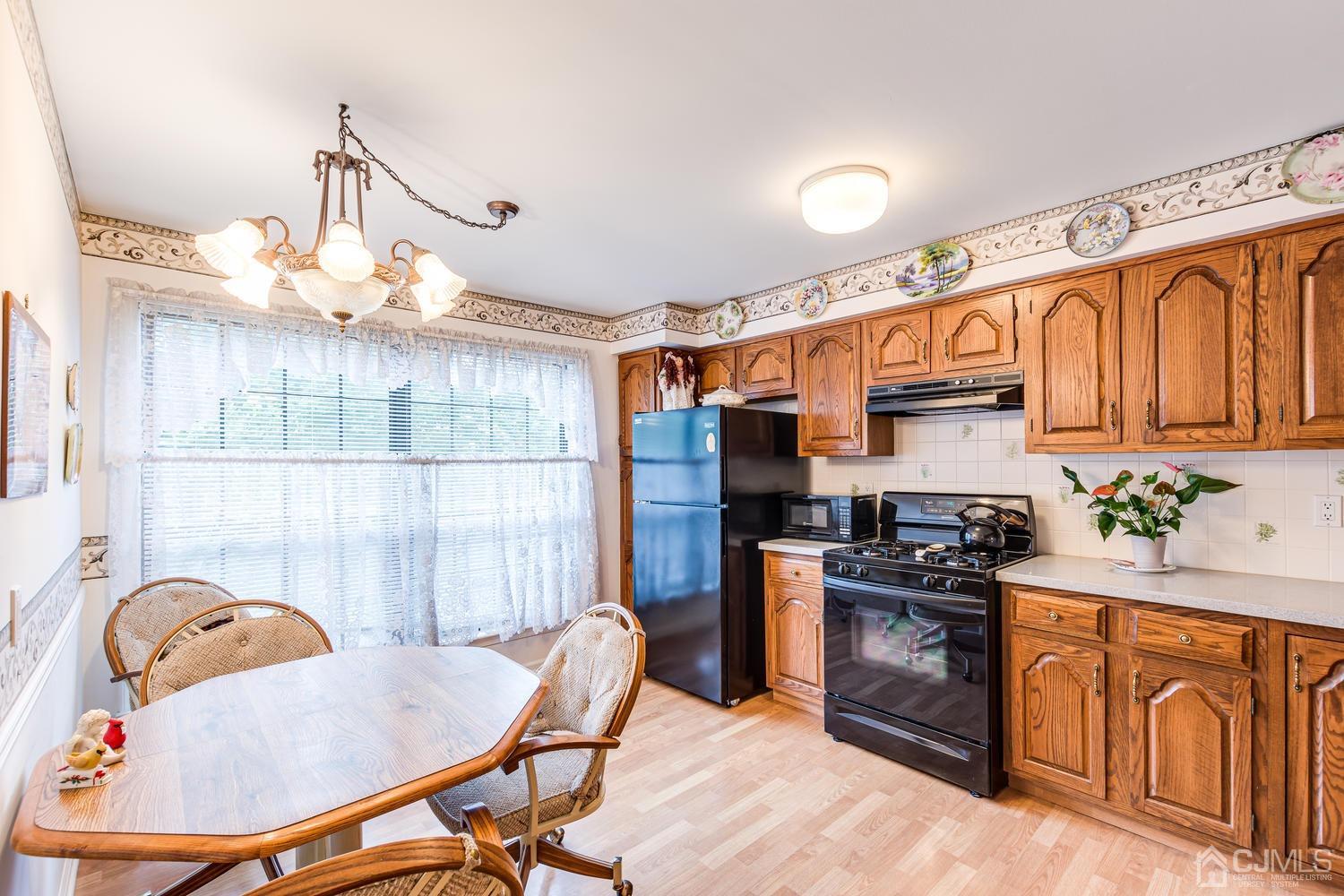 4303 Springbrook Drive Edison, NJ 08820 - Photo 18 of 40 a kitchen with stainless steel appliances a stove a sink dishwasher a dining table and chair with wooden floor