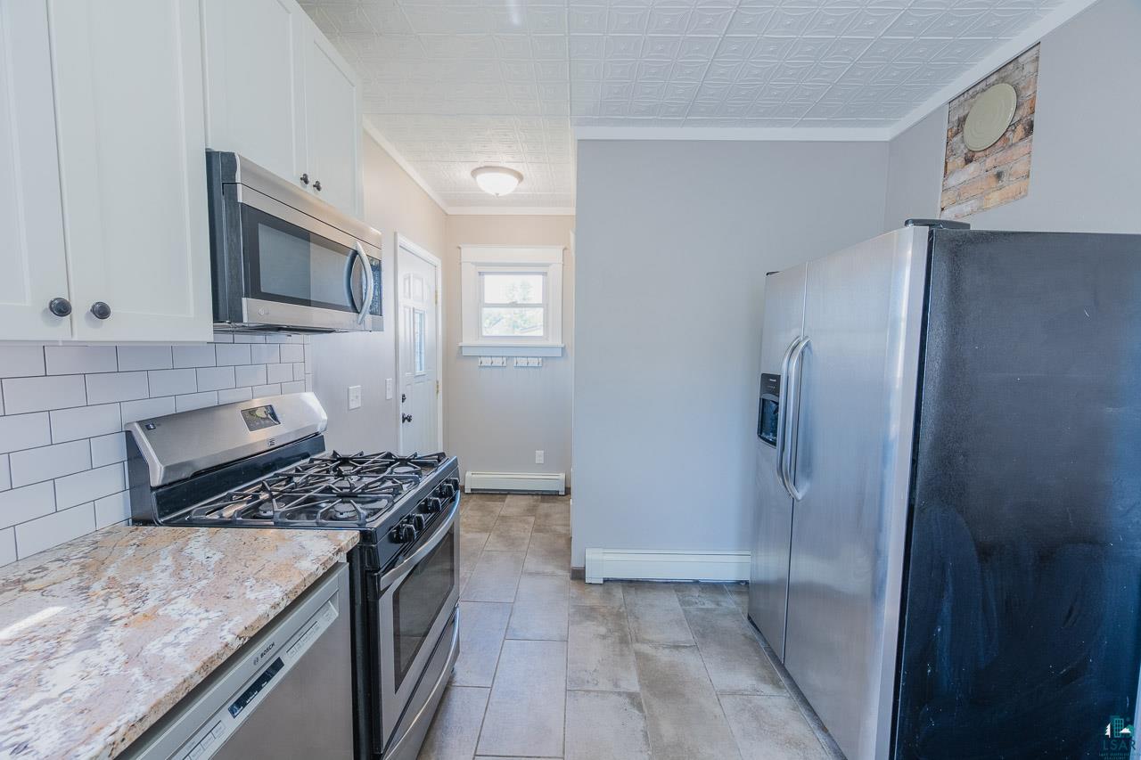 508 10th Street South Virginia, MN 55792 - Photo 12 of 43 Kitchen featuring white shaker cabinetry, subway tile backsplash, granite-style countertops, and stainless steel appliances
