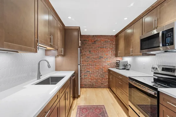 a kitchen with stainless steel appliances a sink a stove top oven a sink a refrigerator cabinets and a dining table