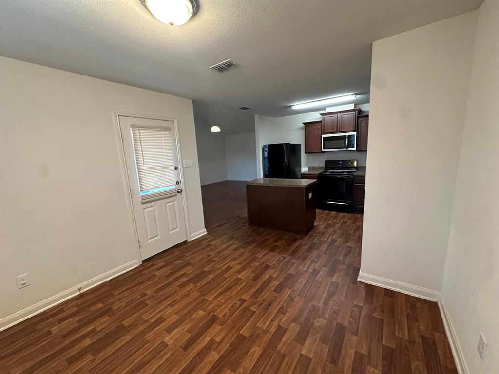 1818 Clegg Street Howe, TX 75459 - Photo 25 of 34 Open-concept kitchen and dining area featuring wood-finish flooring, dark wood cabinetry, and black appliances