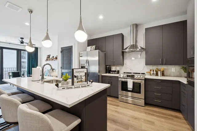 a kitchen with a sink stainless steel appliances and wooden floor