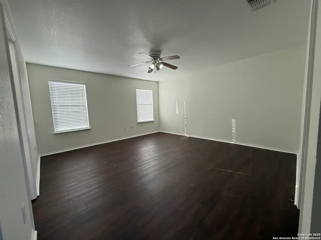 an empty room with wooden floor and windows