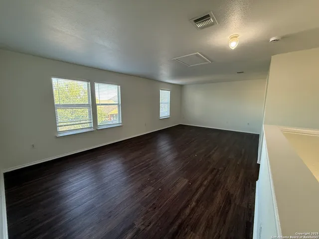 an empty room with wooden floor and windows