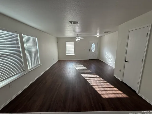 a view of an empty room with wooden floor and windows