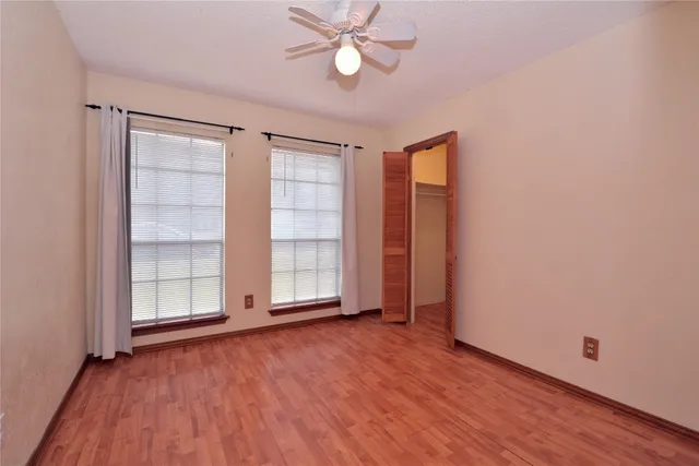 an empty room with wooden floor cabinet and windows