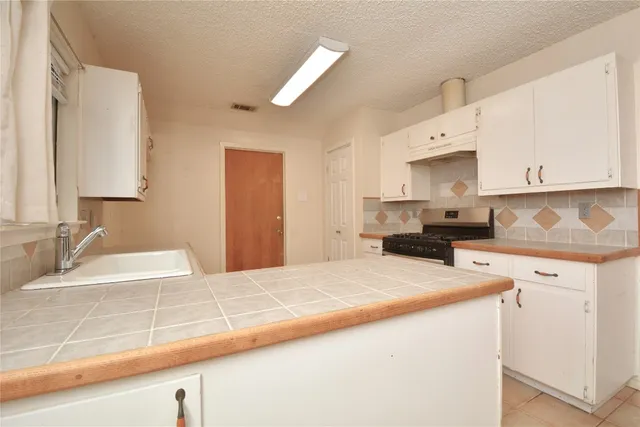 a kitchen with granite countertop a sink a stove and cabinets