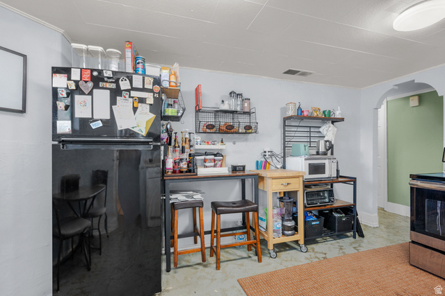 1275 North Geneva Road Provo, UT 84601 - Photo 13 of 25 Kitchen area featuring a black refrigerator, light blue painted walls, and a visible arched doorway