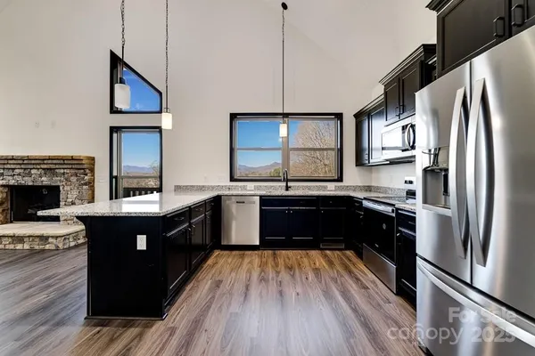 a kitchen with stainless steel appliances granite countertop a refrigerator a sink dishwasher a stove and white countertops with wooden floor