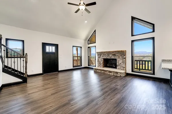 an empty room with wooden floor fireplace and windows