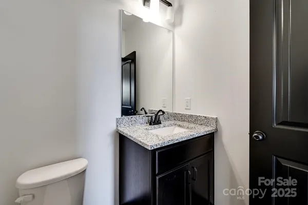a bathroom with a granite countertop sink and a toilet