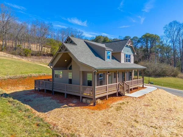 a view of a house with a wooden deck and a big yard
