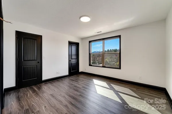 a view of an empty room with window and wooden floor