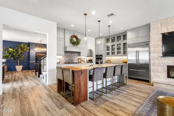a kitchen with stainless steel appliances kitchen island granite countertop a table chairs and a refrigerator