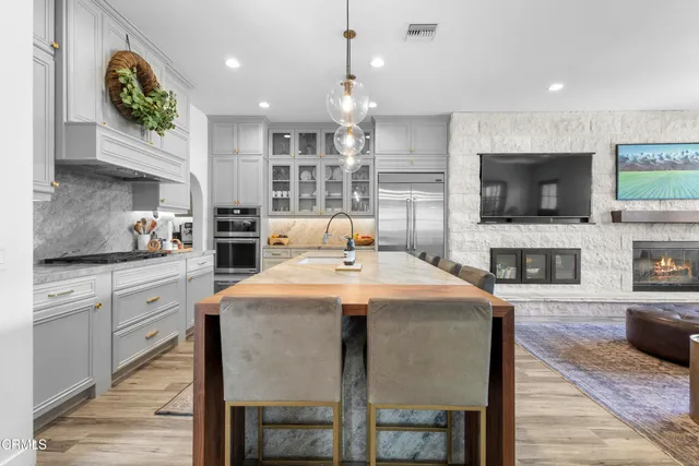 a large kitchen with granite countertop a stove a sink a dining table and chairs with wooden floor