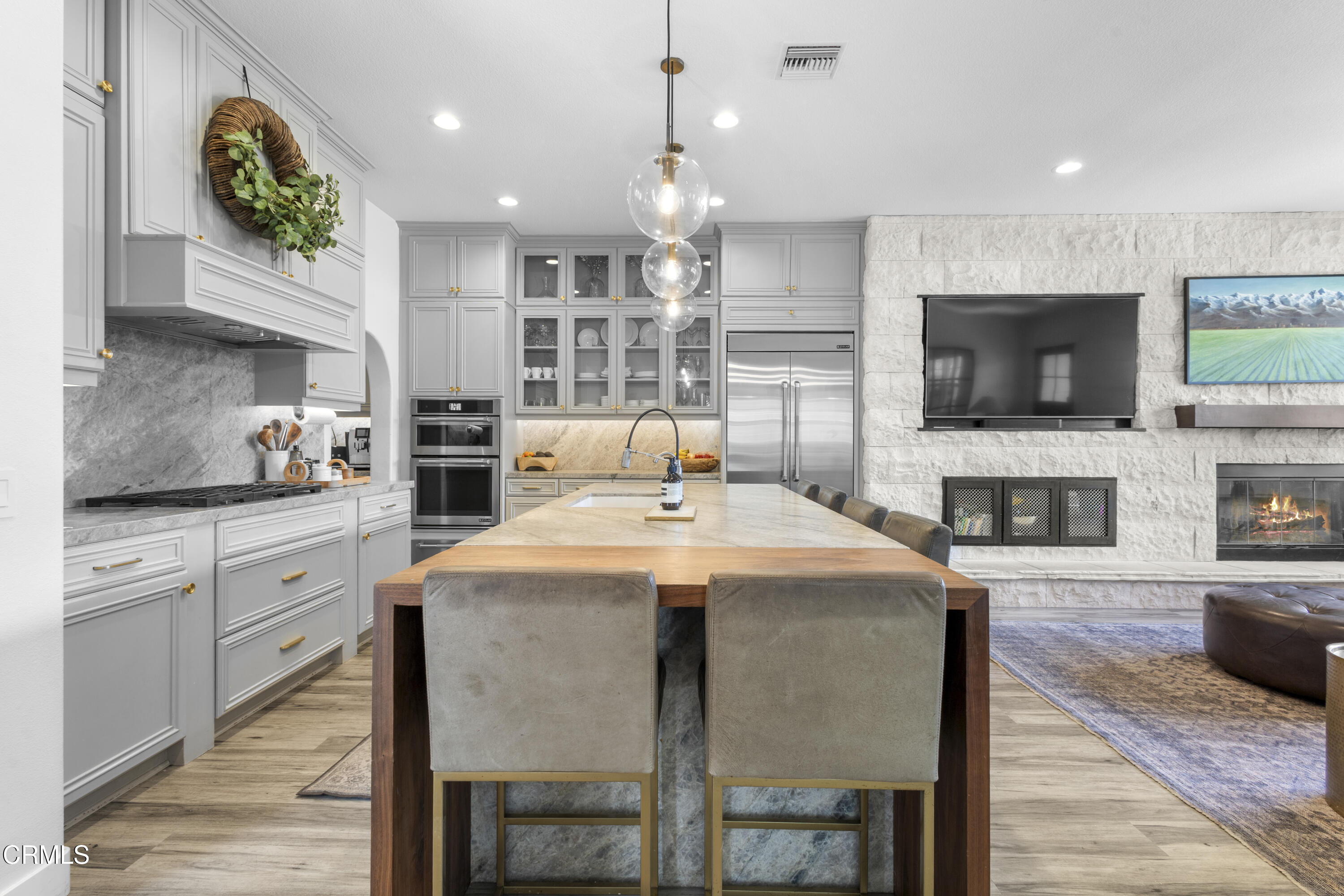 4173 Caribbean Street Oxnard, CA 93035 - Photo 6 of 64 a large kitchen with granite countertop a stove a sink a dining table and chairs with wooden floor
