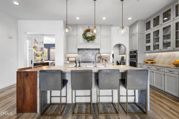 a dining hall with stainless steel appliances kitchen island granite countertop a dining table chairs and sink