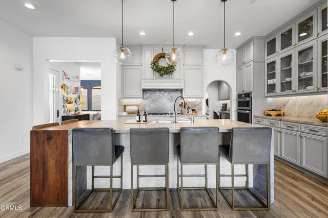 a dining hall with stainless steel appliances kitchen island granite countertop a dining table chairs and sink