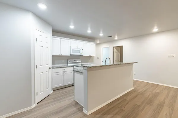 a kitchen with stainless steel appliances granite countertop a refrigerator sink and white cabinets