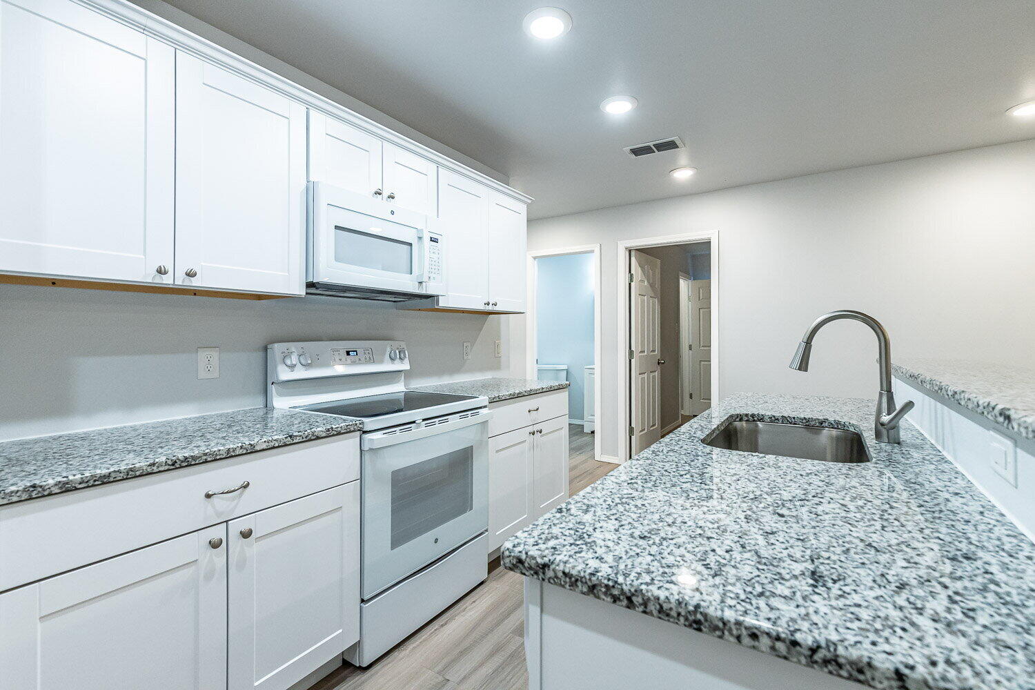 5517 Kemper Street, Unit A Lubbock, TX 79416 - Photo 6 of 25 a kitchen with stainless steel appliances granite countertop a sink a stove and white cabinets