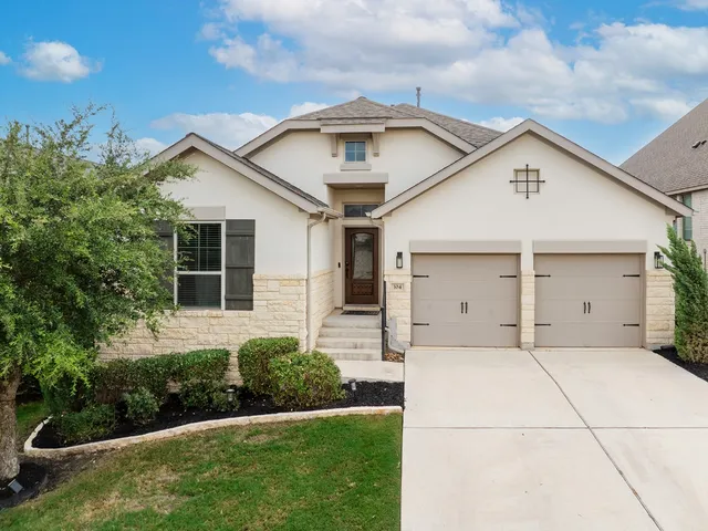 a view of a white house next to a yard and large trees
