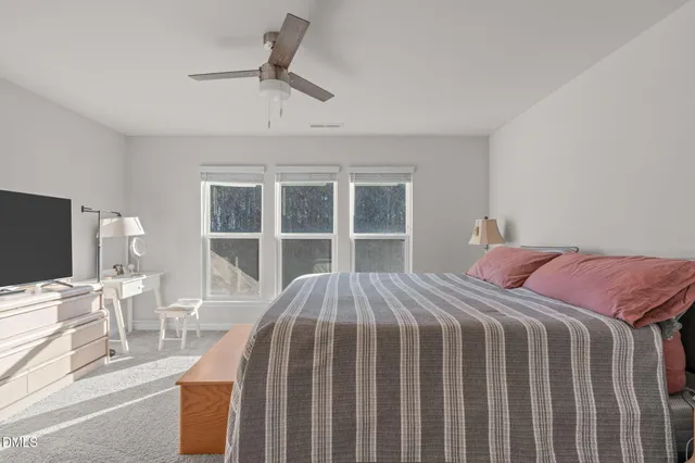 a bed sitting in a bedroom next to a window with a chair and table