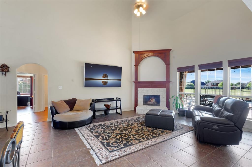 10414 Broadmoor Lane Rowlett, TX 75089 - Photo 12 of 38 Tiled living room featuring arched walkways, a glass covered fireplace, and a high ceiling