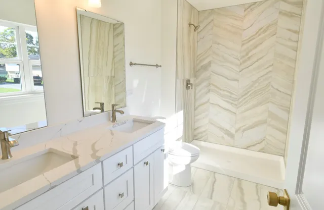 a bathroom with a granite countertop sink a toilet and shower