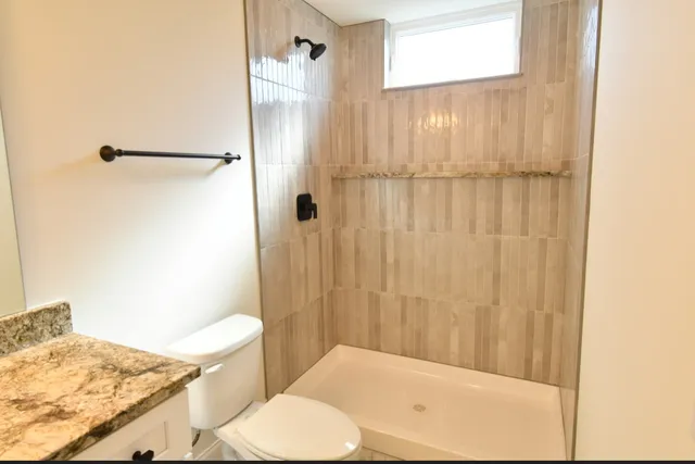 a bathroom with a granite countertop sink toilet and shower