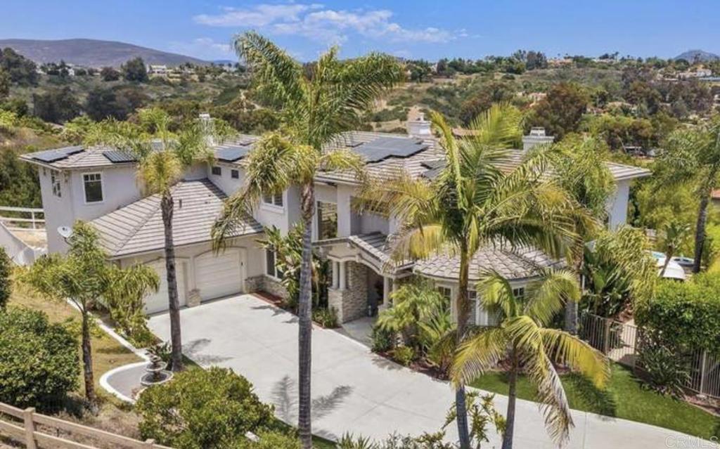 an aerial view of a house with a yard and mountain view in back