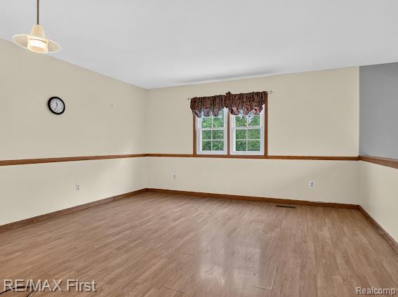56375 Bates Road New Baltimore, MI 48051 - Photo 23 of 35 Spacious room featuring warm wood-finish flooring, cream and taupe two-tone walls with wood chair rail detailing, and large double-hung windows with brown valance drapery