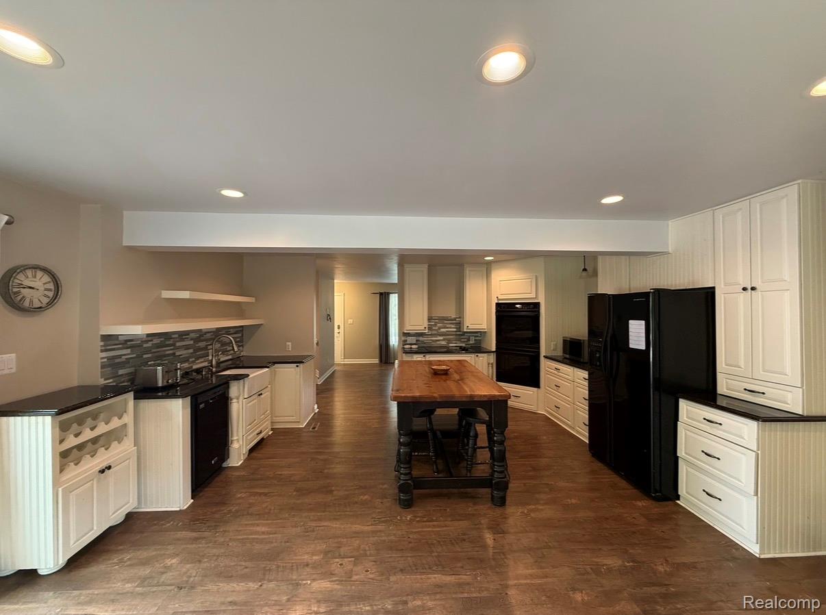 2360 Oklahoma Avenue Rochester, MI 48309 - Photo 19 of 36 Spacious kitchen featuring wood-finish flooring, white cabinetry, dark countertops, and a central island with a wood top