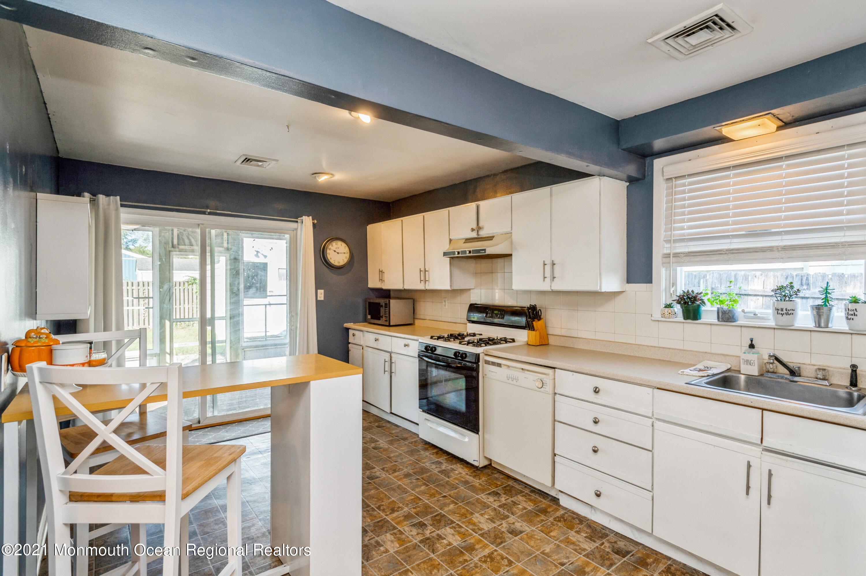 542 Lloyd Road Toms River, NJ 08753 - Photo 3 of 20 a kitchen with stainless steel appliances granite countertop a stove a sink dishwasher and white cabinets with wooden floor