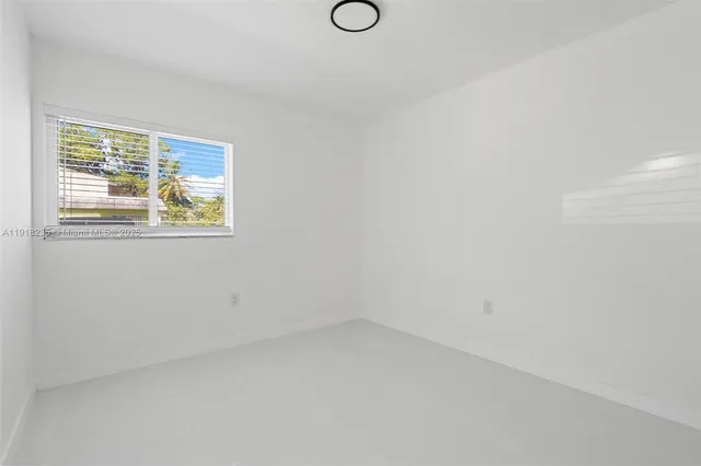 a view of an empty room with wooden floor and windows