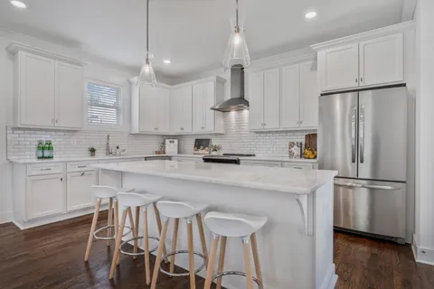 a kitchen with stainless steel appliances a refrigerator a stove a sink and chairs with wooden floor