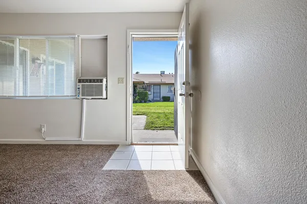 an empty room with a window and a kitchen view