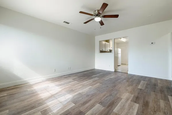 a view of a big room with wooden floor and a ceiling fan