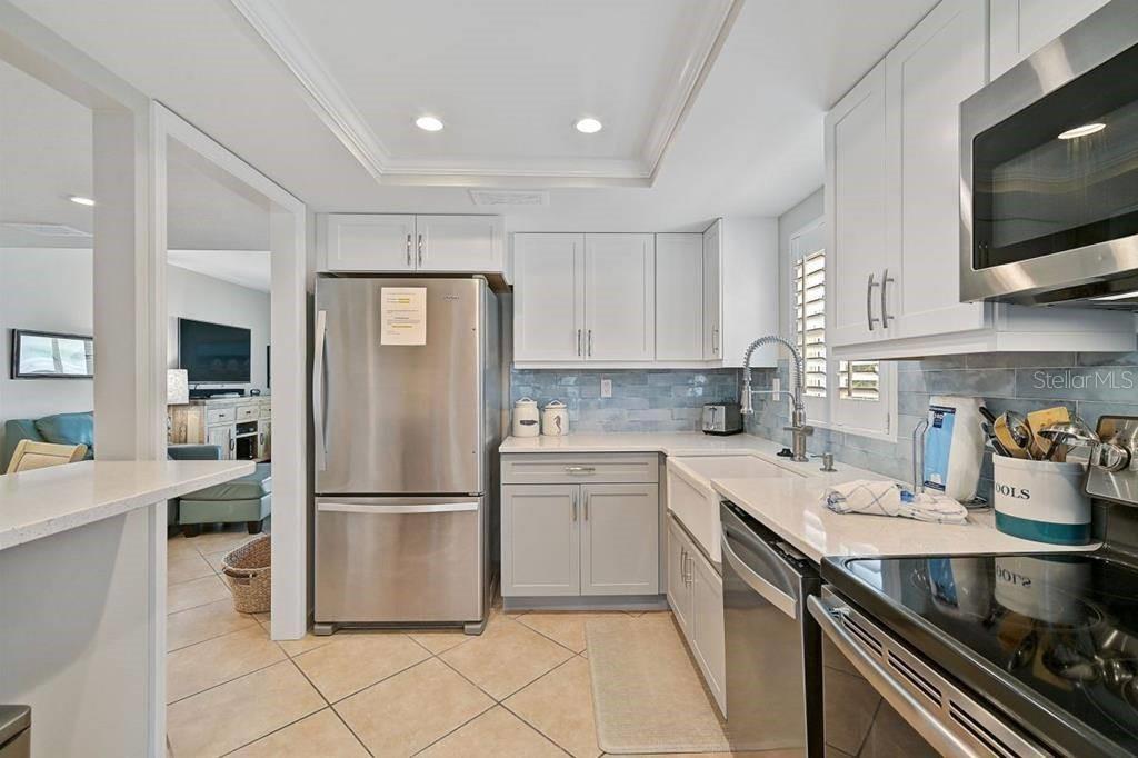 6154 Midnight Pass Road, Unit 206 Sarasota, FL 34242 - Photo 5 of 9 a kitchen with a sink stainless steel appliances and white cabinets