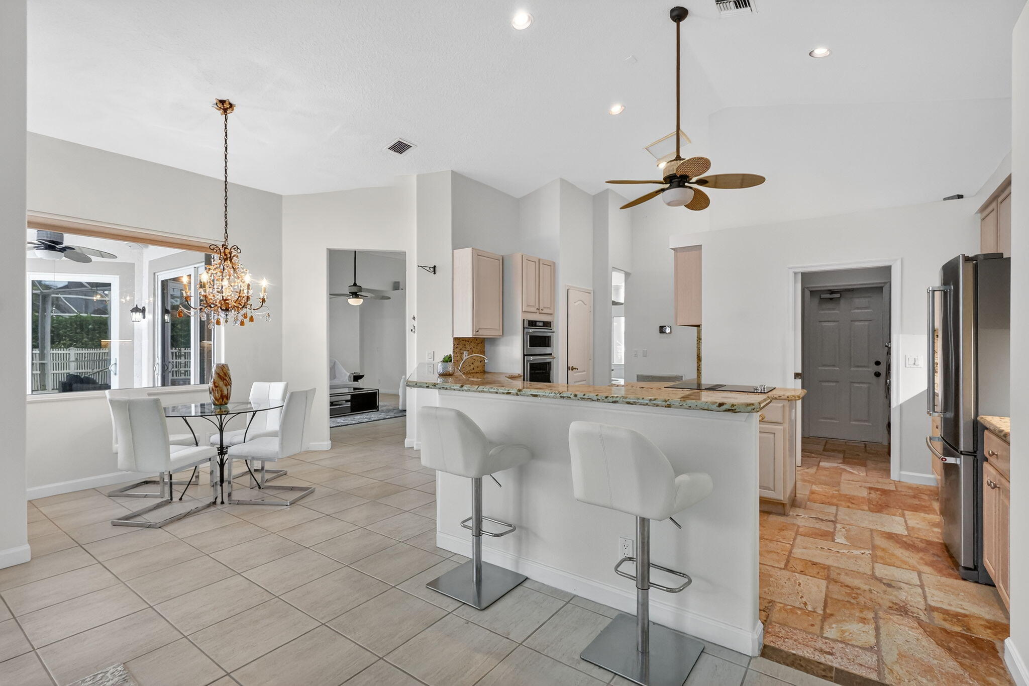 18981 Southeast Outrigger Lane Jupiter, FL 33458 - Photo 27 of 79 a kitchen with stainless steel appliances kitchen island granite countertop a dining table chairs and a chandelier
