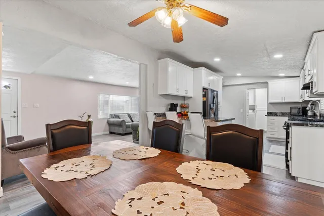 a kitchen with stainless steel appliances kitchen island granite countertop a refrigerator a stove a sink dishwasher a dining table and chairs with wooden floor