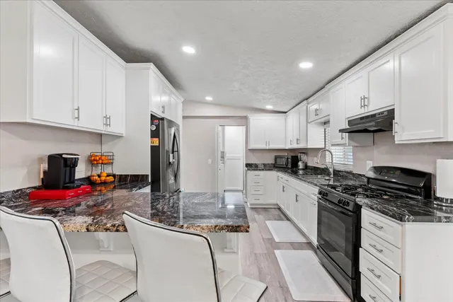 a kitchen with granite countertop a sink stove and cabinets